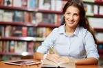 Portrait of pretty student looking at camera while working in college library